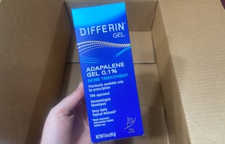 hand holding differin adapalene retinoid acne gel over an amazon box