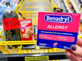 Someone holding up a box of Benadryl allergy medication next to a cart at Dollar General