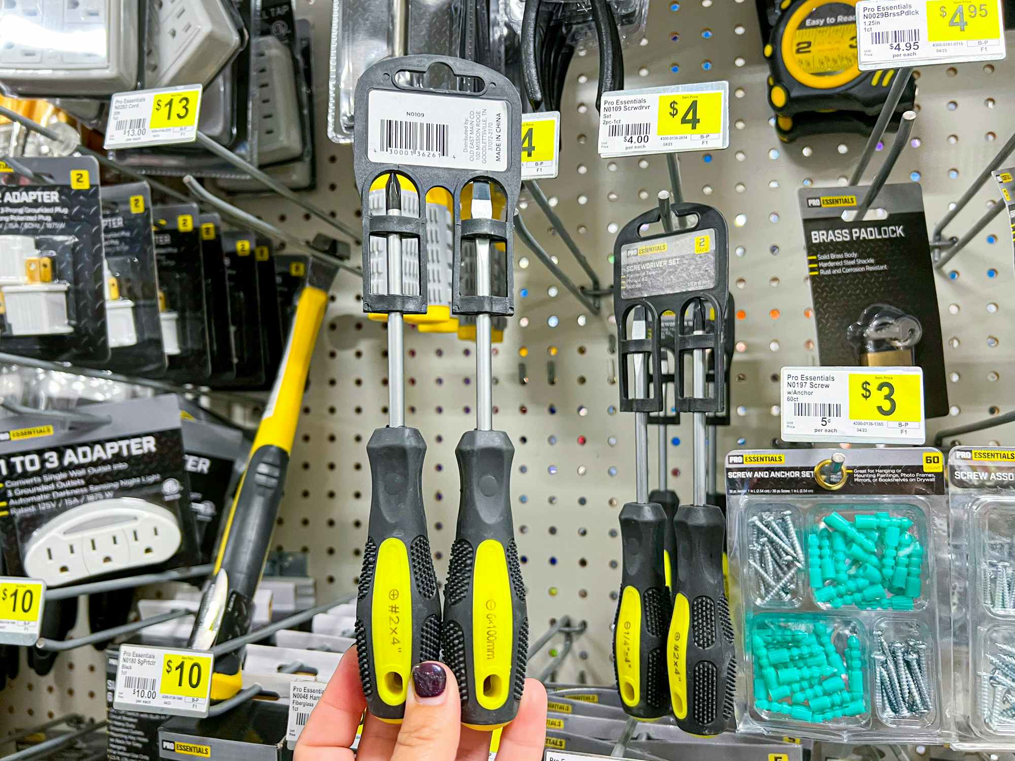 Someone holding a 2-pack of DG Home screwdrivers in the tool aisle at Dollar General