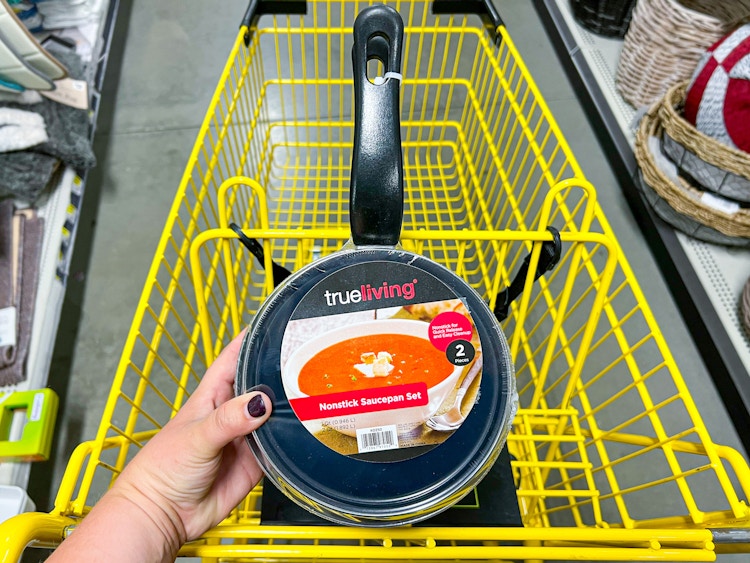 Someone holding a 2pk of Trueliving sauce pans over a Dollar General shopping cart