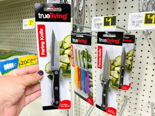 Someone holding a Trueliving paring knife next to its peg on the wall in Dollar General