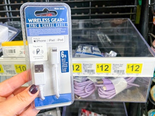 Someone holding up a Wireless Gear iPhone charger next to a shelf at Dollar General
