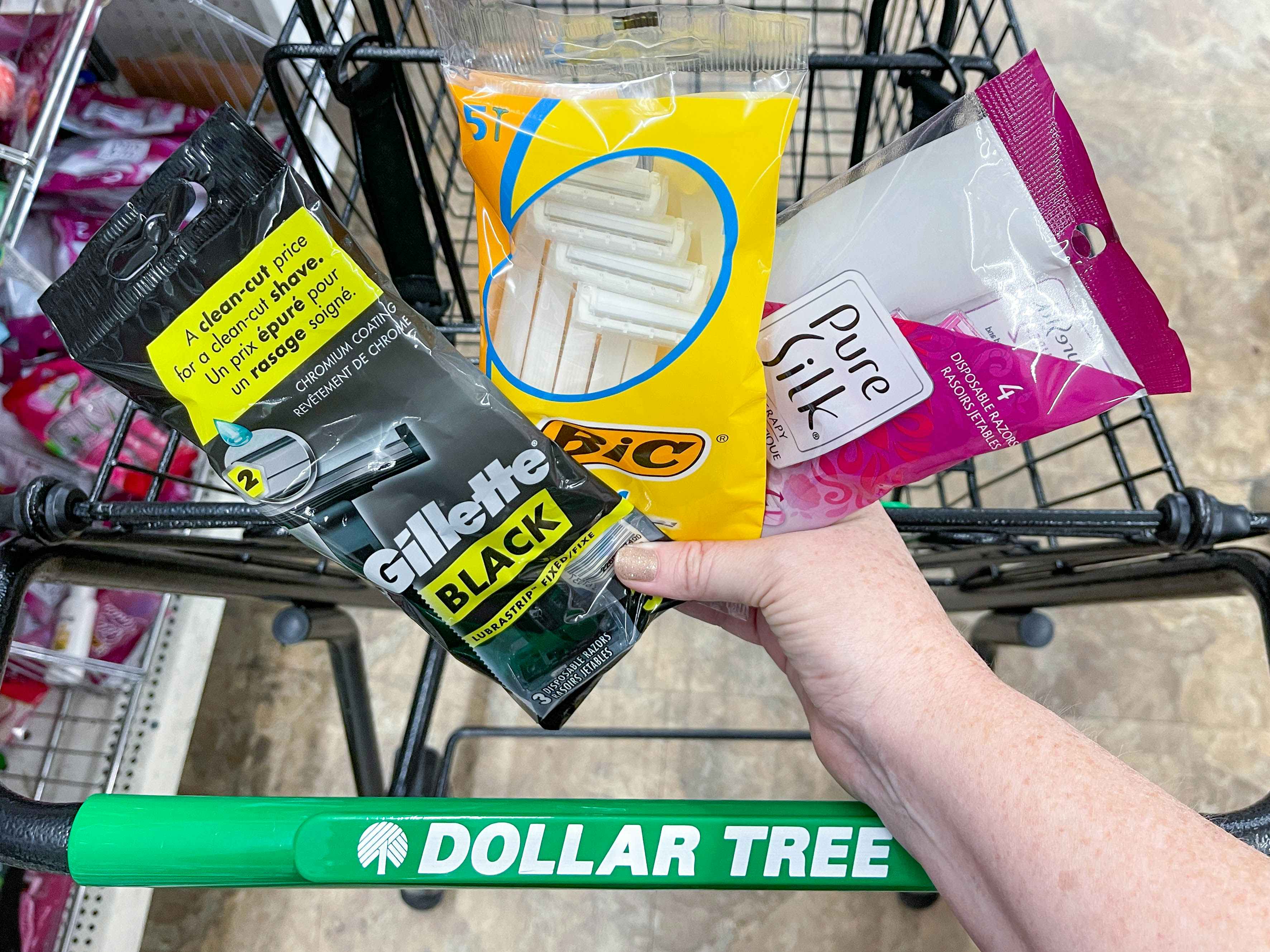 a person holding razor packages in front of dollar tree cart