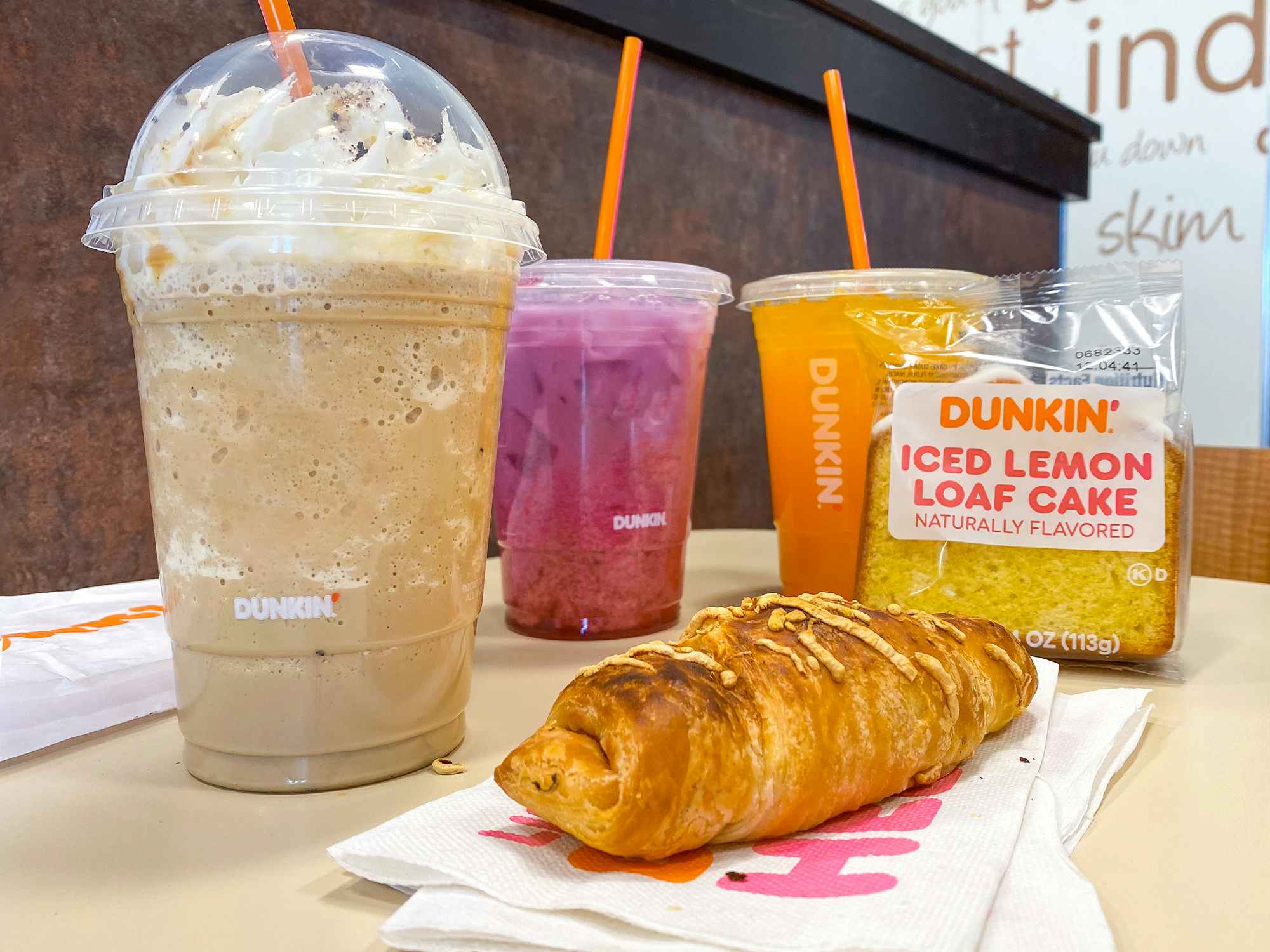 dunkin donuts refreshers, croissant stuffer, iced lemon loaf cake, and frozen butter pecan swirl drink in restaurant