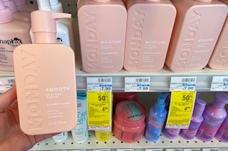 hand holding a bottle of Monday hair care next to sale tags at cvs