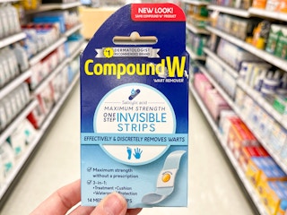 Someone holding Compound W wart remover strips in a store