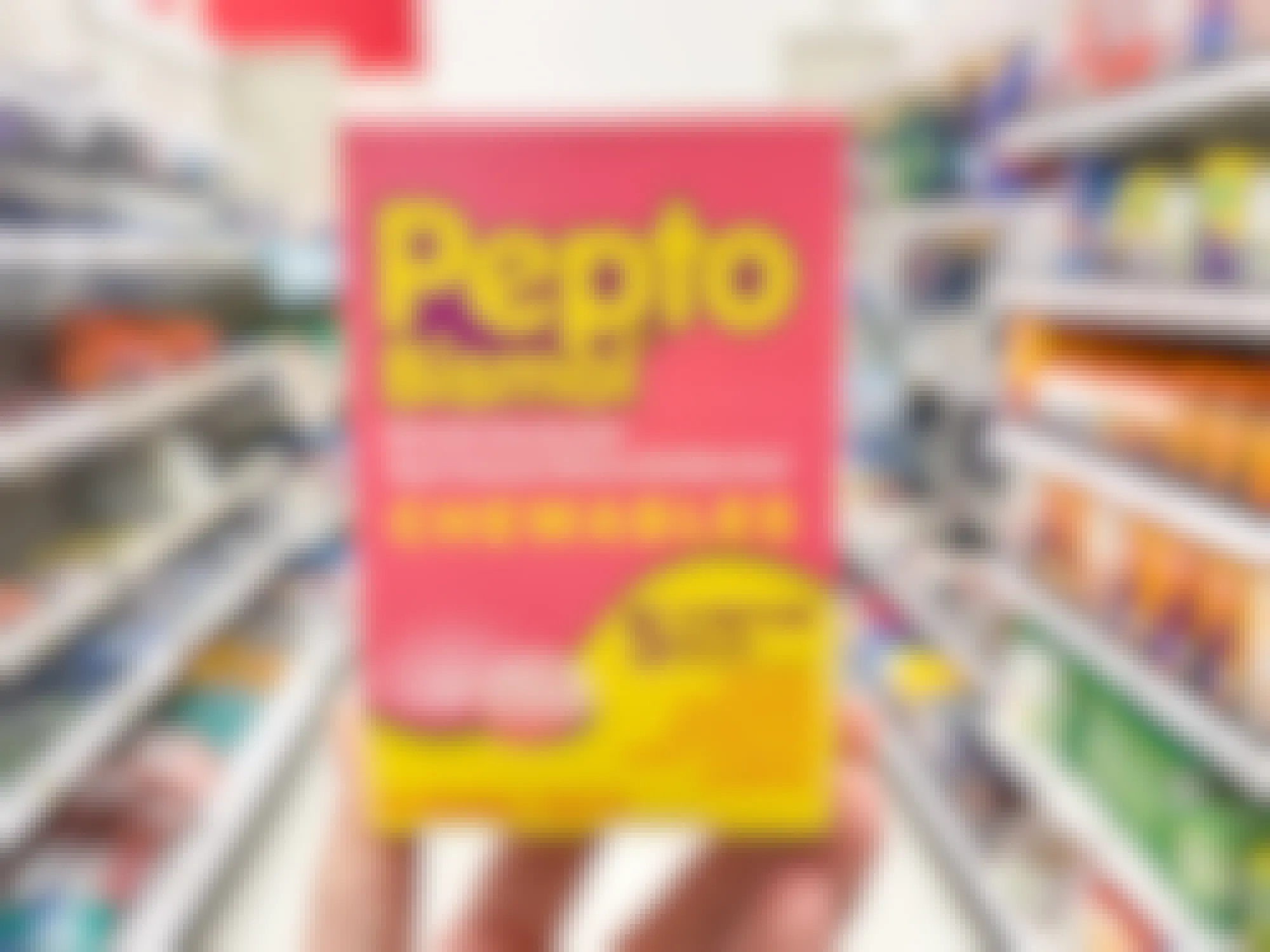 Someone holding a box of chewable Pepto Bismol tablets in a store