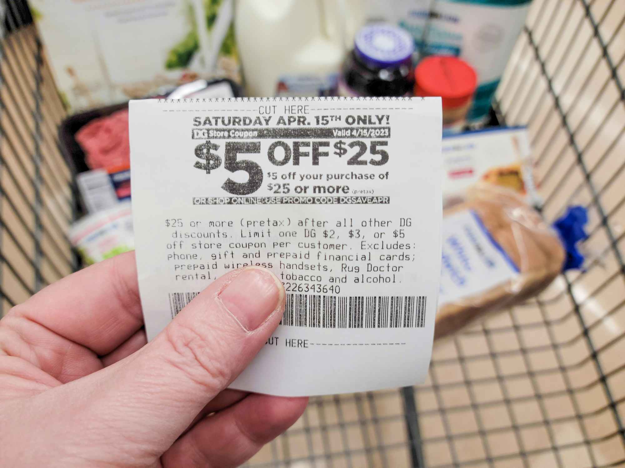 Someone holding a coupon in front of Food Lion groceries in a shopping cart