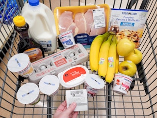 Someone holding a coupon in front of Food Lion groceries in a shopping cart