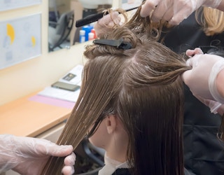 Someone getting their hair worked on by a few cosmetology students