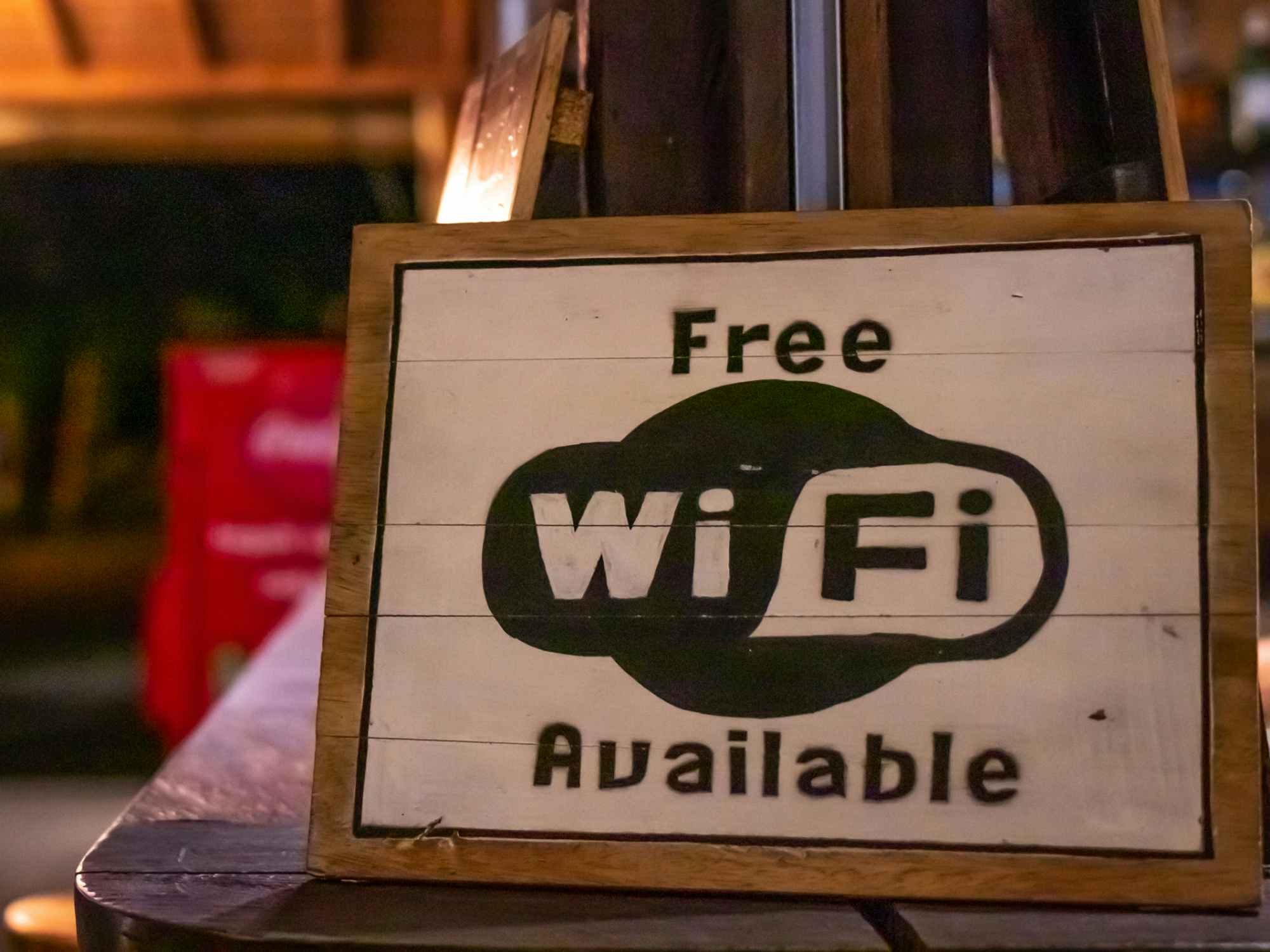A sign reading free wifi available with a coffee shop in the background