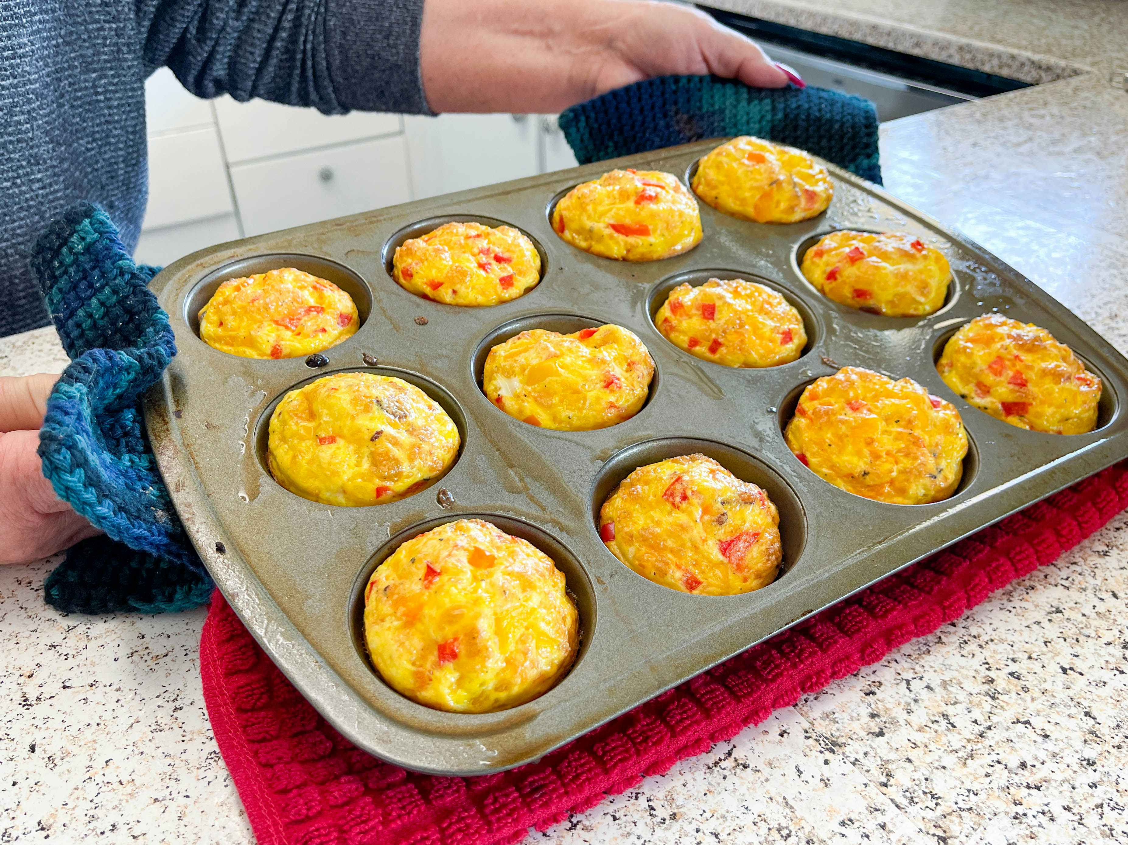 a person holding a muffin tray of egg muffins 