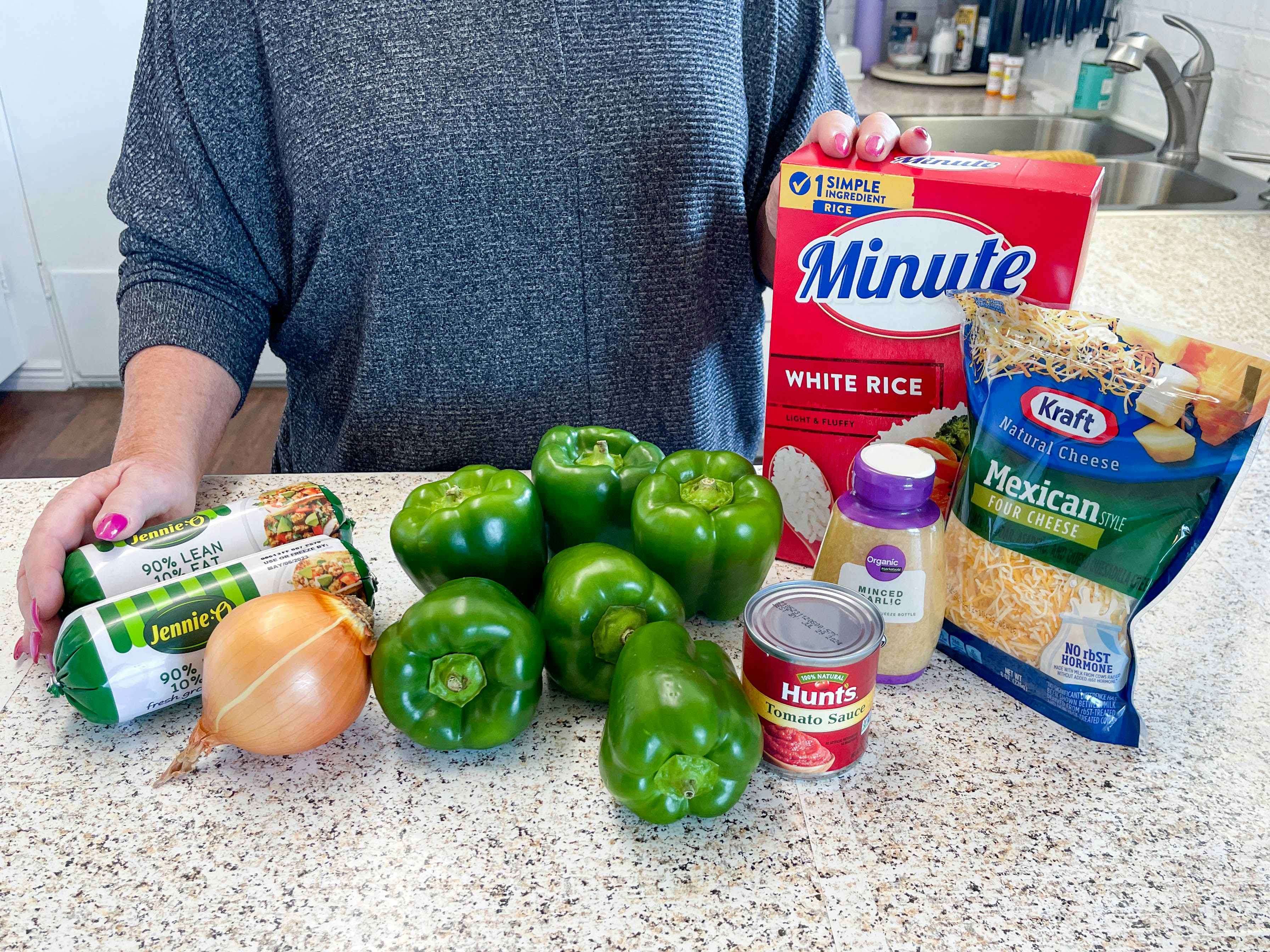 a person with ingredients to make stuffed peppers 