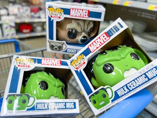 A variety of Funko mugs sitting in a store cart with store shelves in the background.