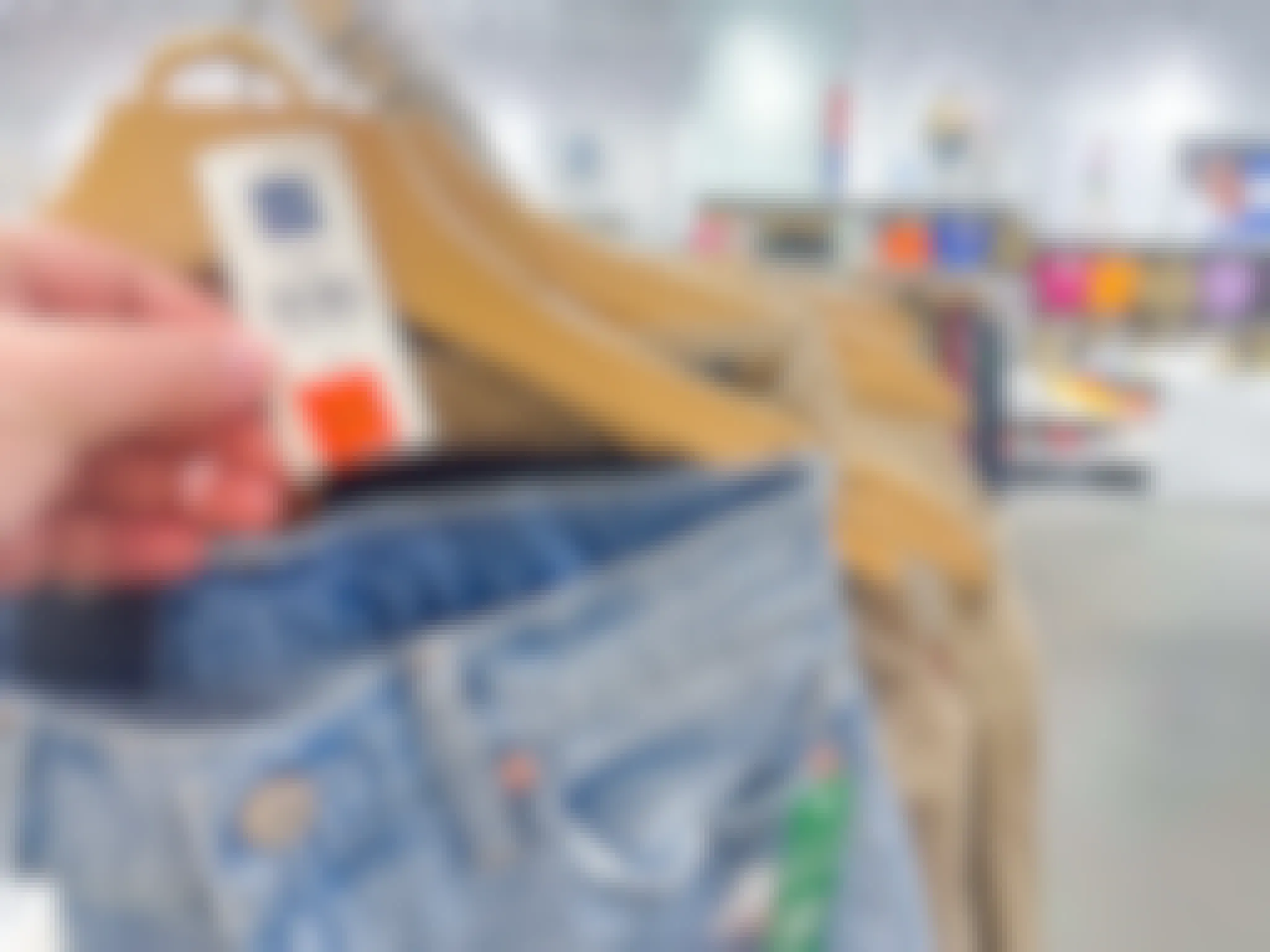 a person holding a gap orange tag on a pair of jeans on rack in store 