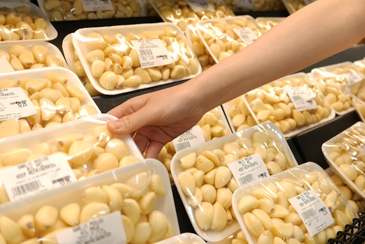 Hand picking up a pack of garlic cloves