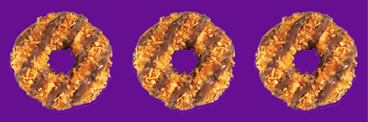 Three Girl Scout Samoas cookies on a purple background