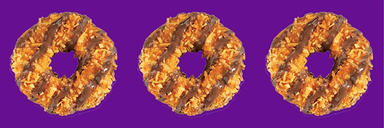 Three Girl Scout Samoas cookies on a purple background