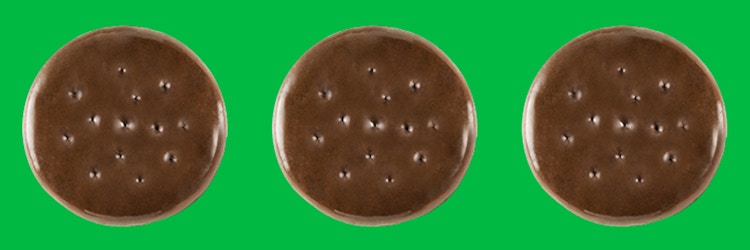 Three Girl Scout Thin Mints cookies on a green background