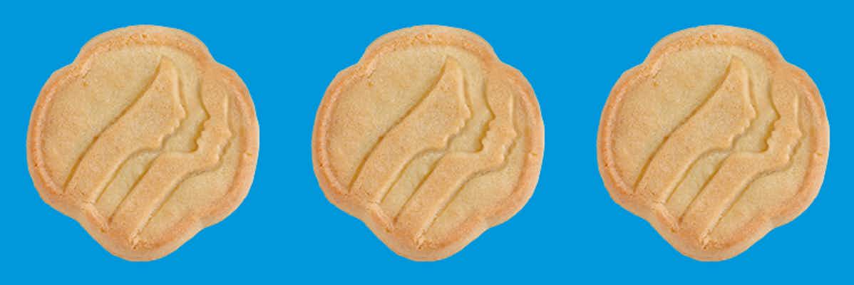 Three Girl Scout Trefoils cookies on a blue background