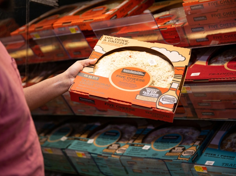 Person grabbing a five cheese walmart pizza from a cooler