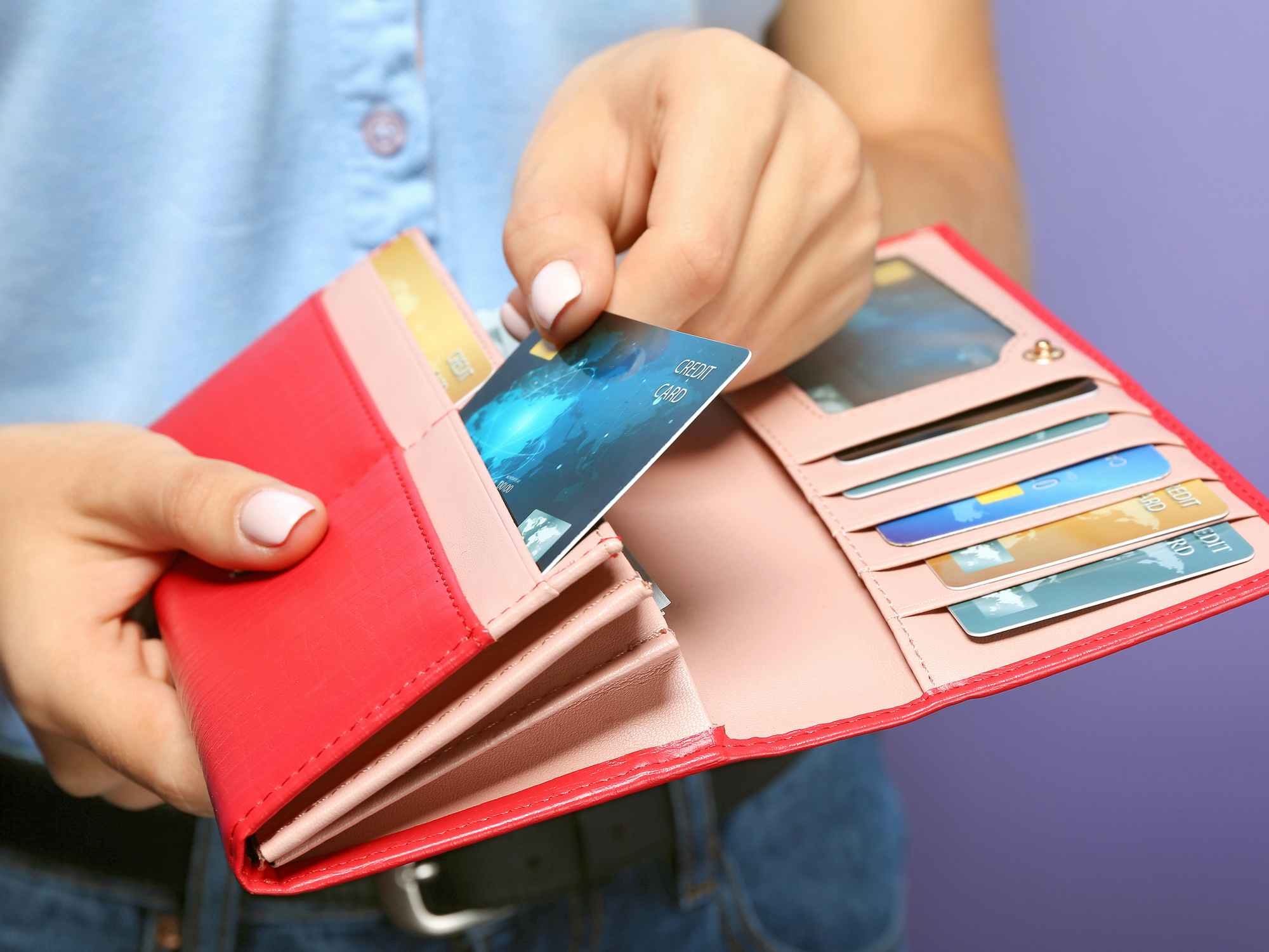 person taking credit card from pink wallet