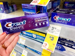 hand holding crest toothpaste next to sales tag