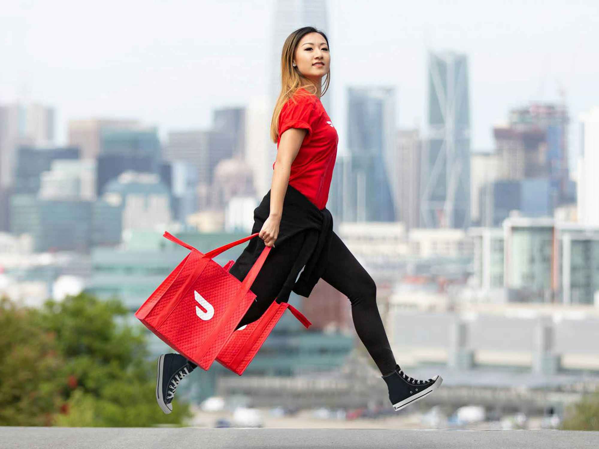 person carrying doordash bags in city