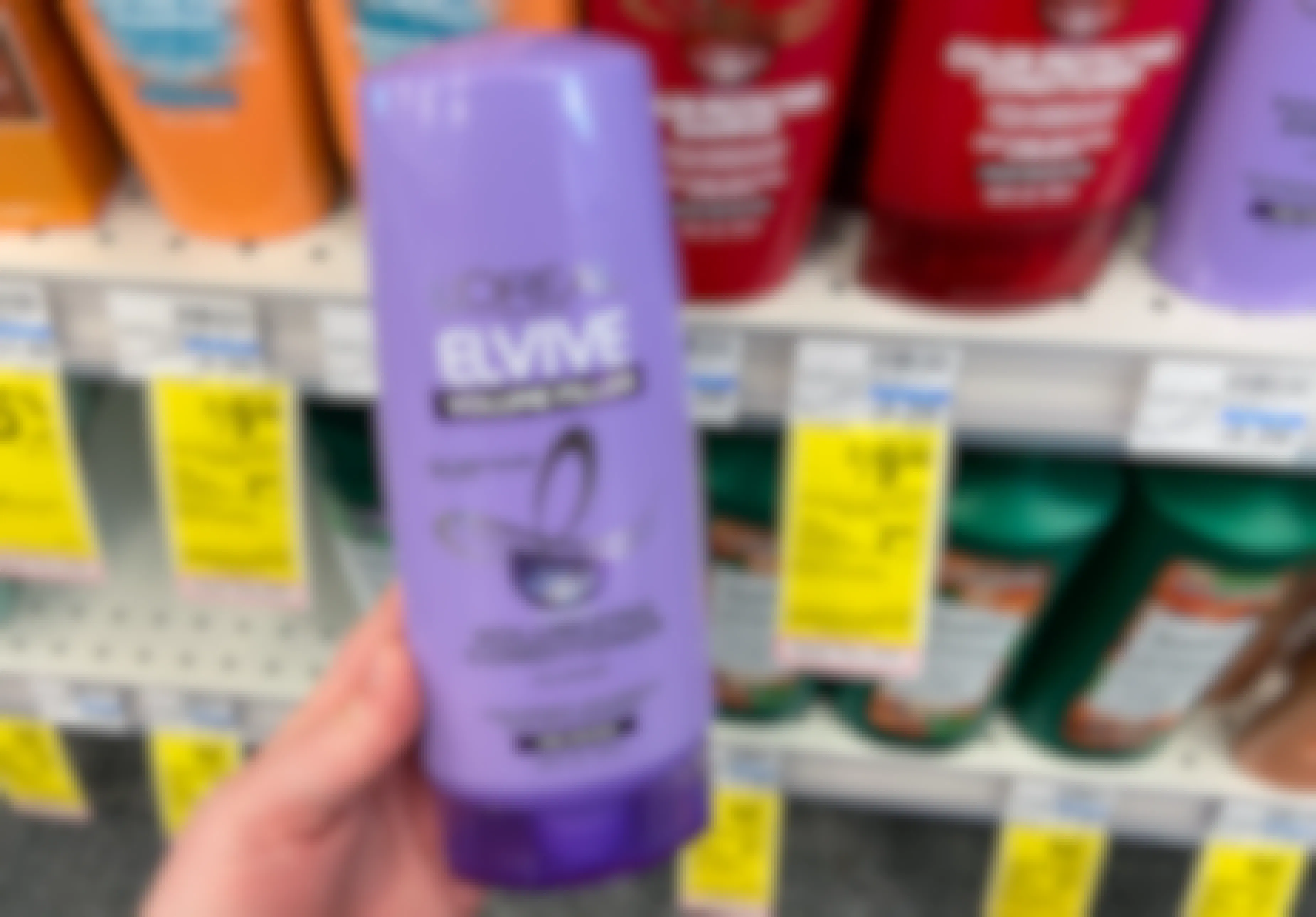 hand holding a bottle of l'oreal elvive hair care next to a sale tag at cvs