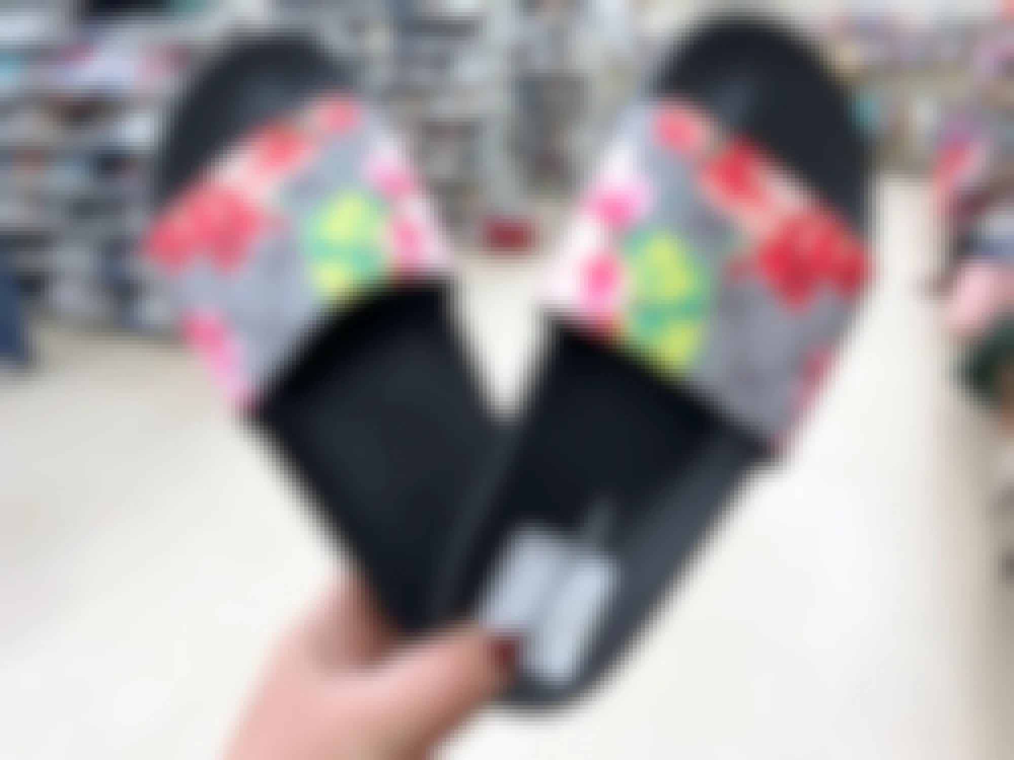 person holding a pair of floral gucci slides at a thrift store
