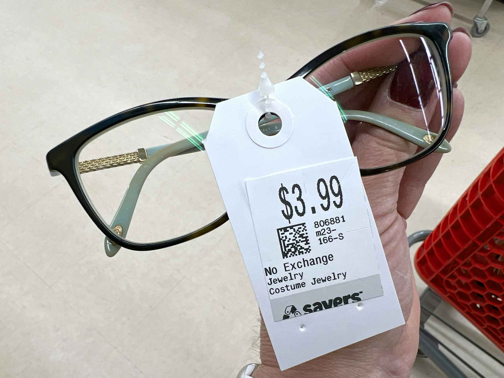 person holding a pair of tiffany reading glasses at a thrift store