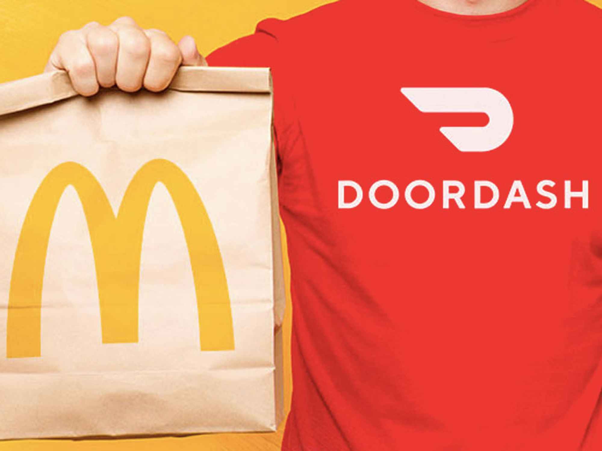 a person wearing a doordash t shirt holding up a mcdonalds bag