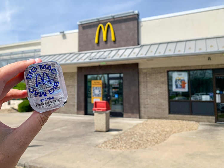 a person holding big mac sauce outside of a McDonald's 