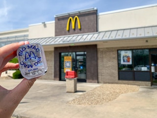 a person holding big mac sauce outside of a McDonald's