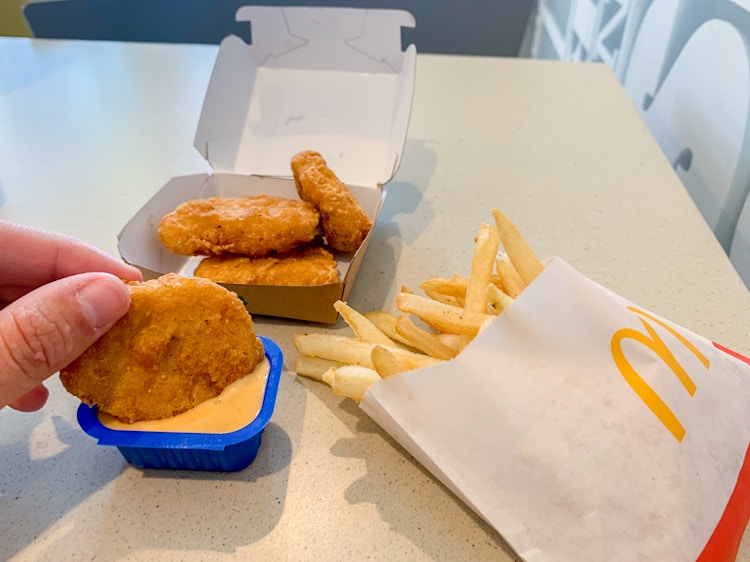 a person dunking a chicken nugget into big mac sauce at McDonald's 