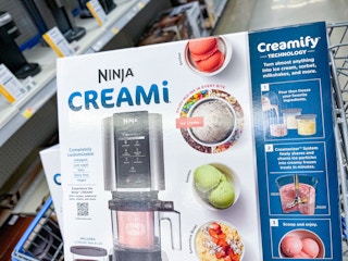 A Ninja Creami lying atop another Ninja Cream box in a store cart.