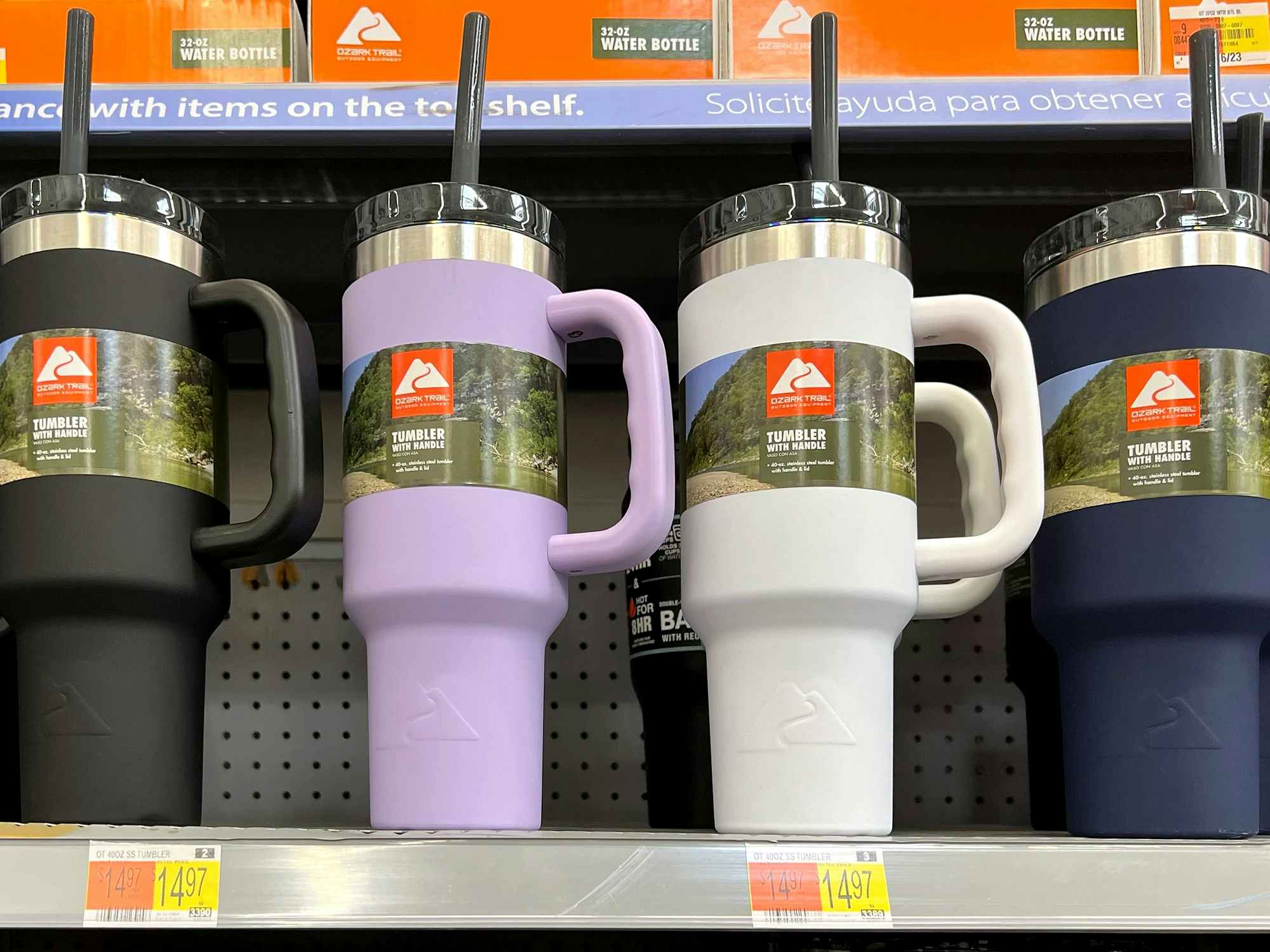 four ozark trail tumblers with lids, straws, and handles on a walmart shelf with price tags of $14.97