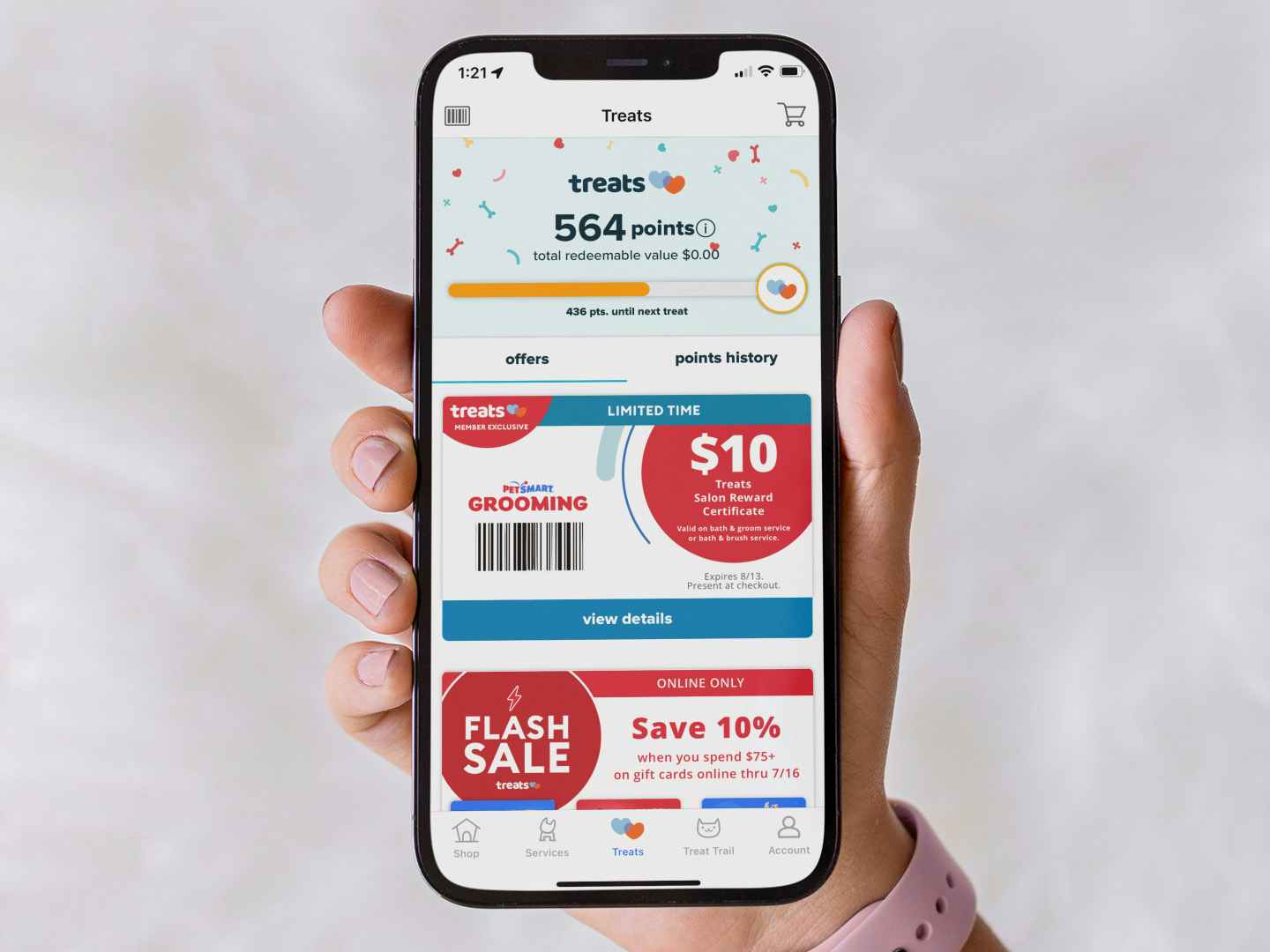 Someone holding up a Petsmart grooming coupon in the offers section of the app