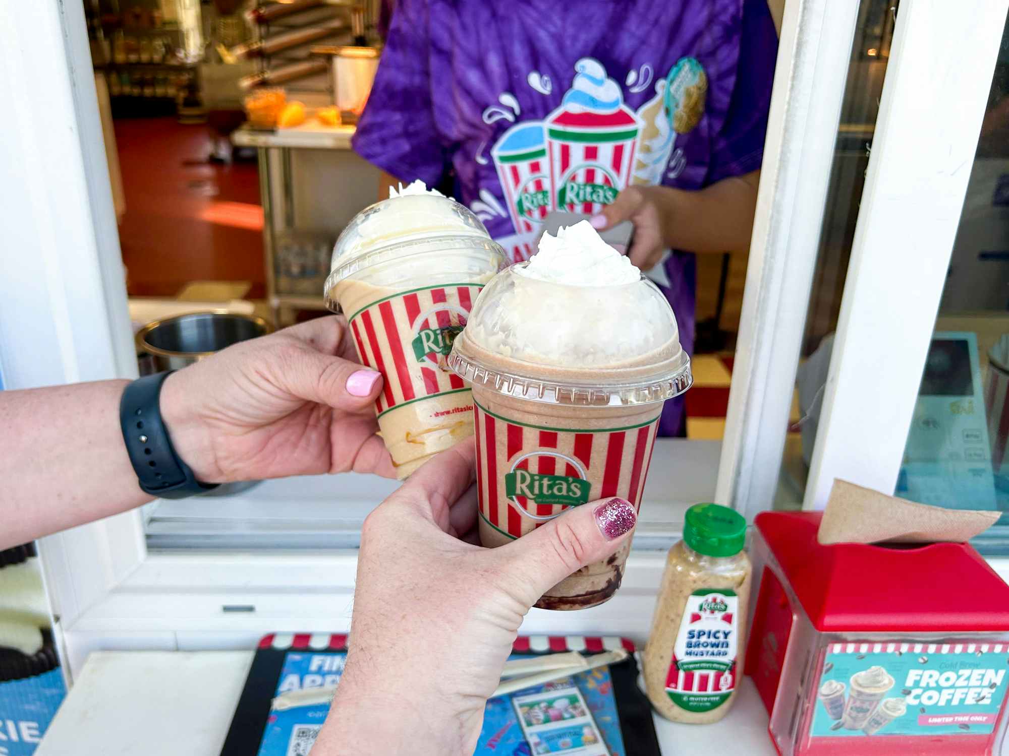 Two people holding frozen coffees at Rita's