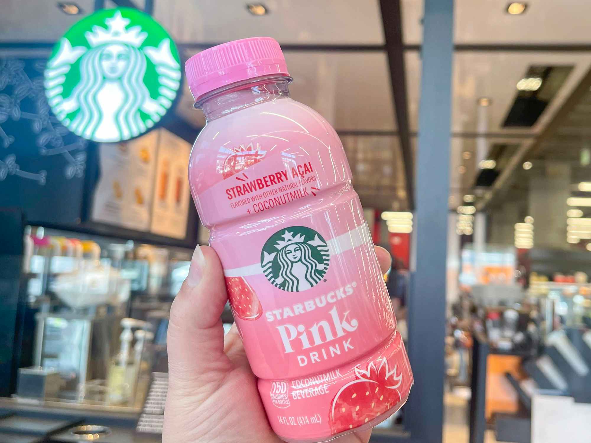 Someone holding a Starbucks bottled Pink Drink in a store