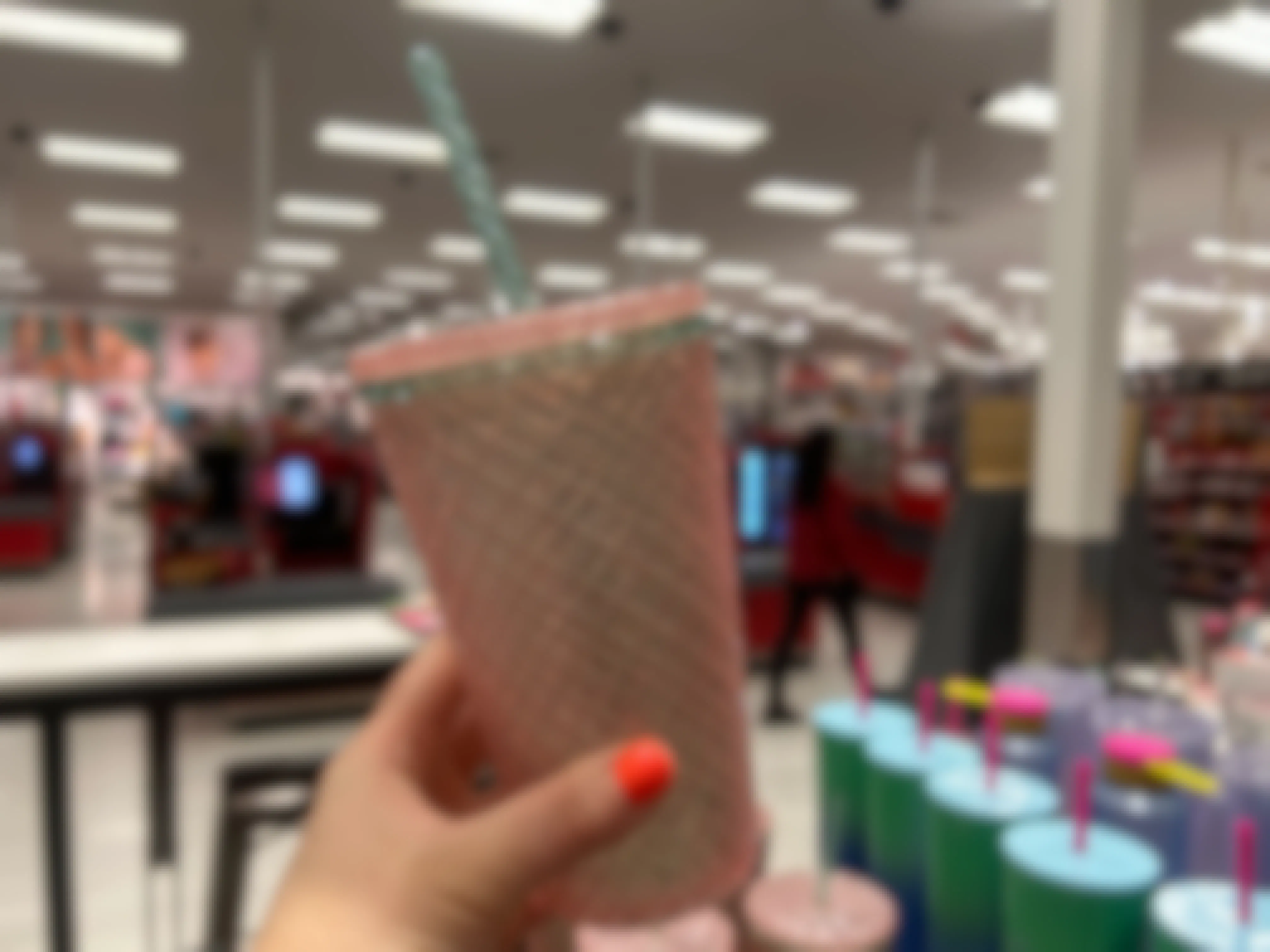 person holding an exclusive starbucks summer cup at a target. the cup is a pink and green grid cold cup