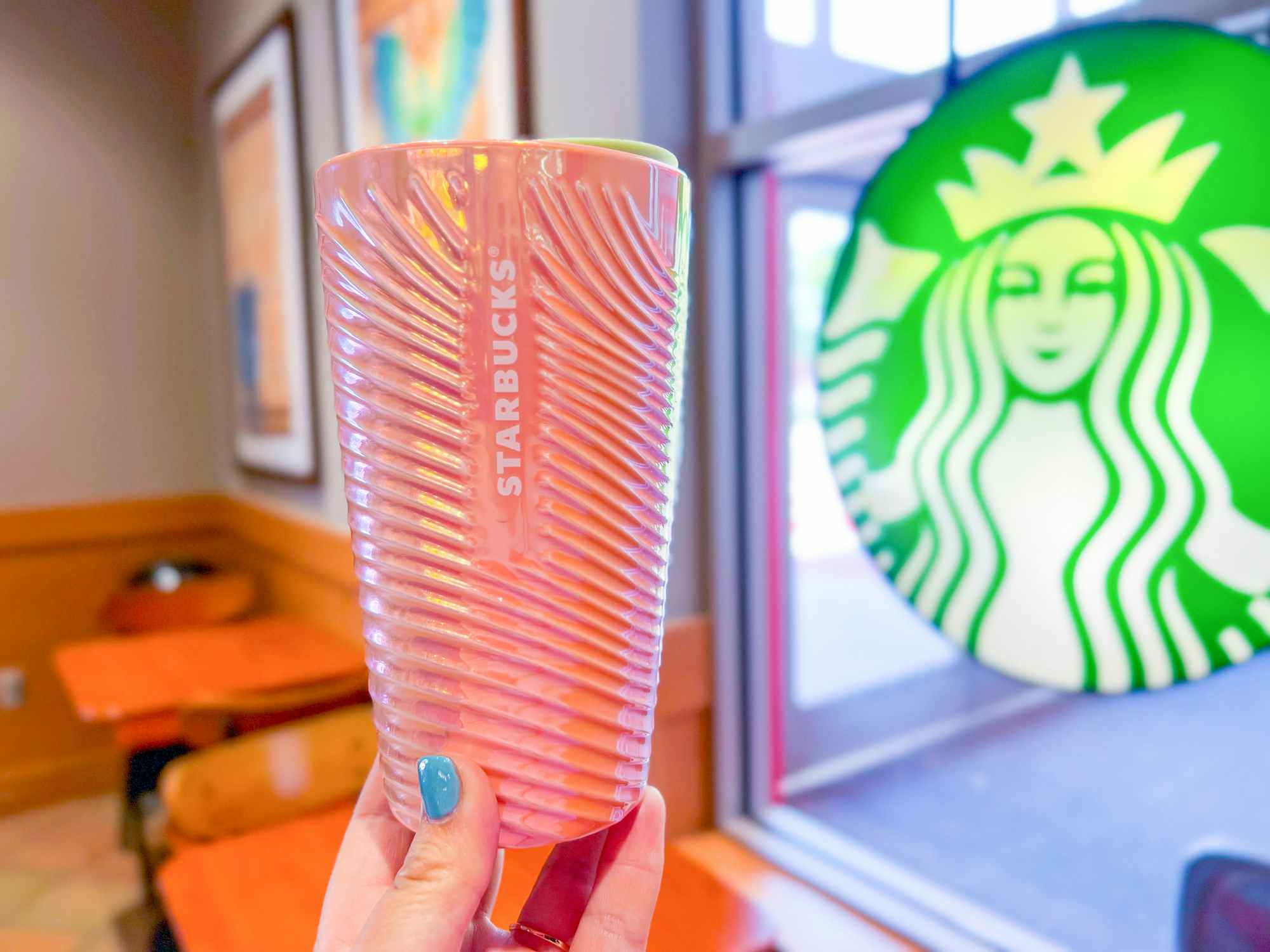 Someone holding a Starbucks Summer cup inside a Starbucks