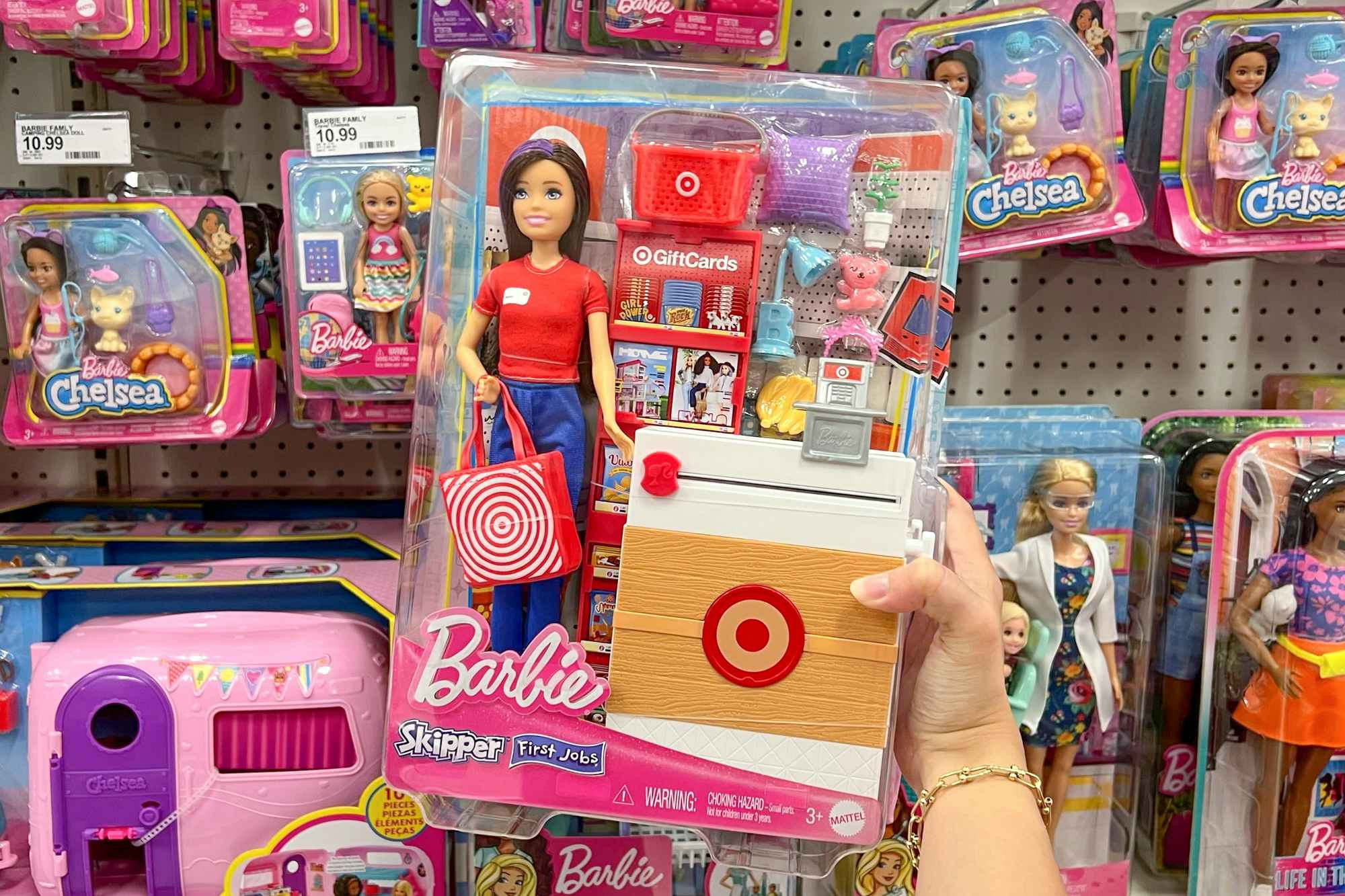 Someone holding a Target Barbie doll in front of a shelf