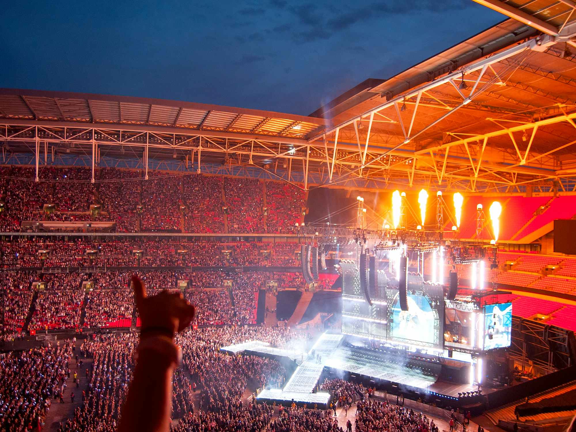 taylor swift performing on stage at a stadium with large crowd