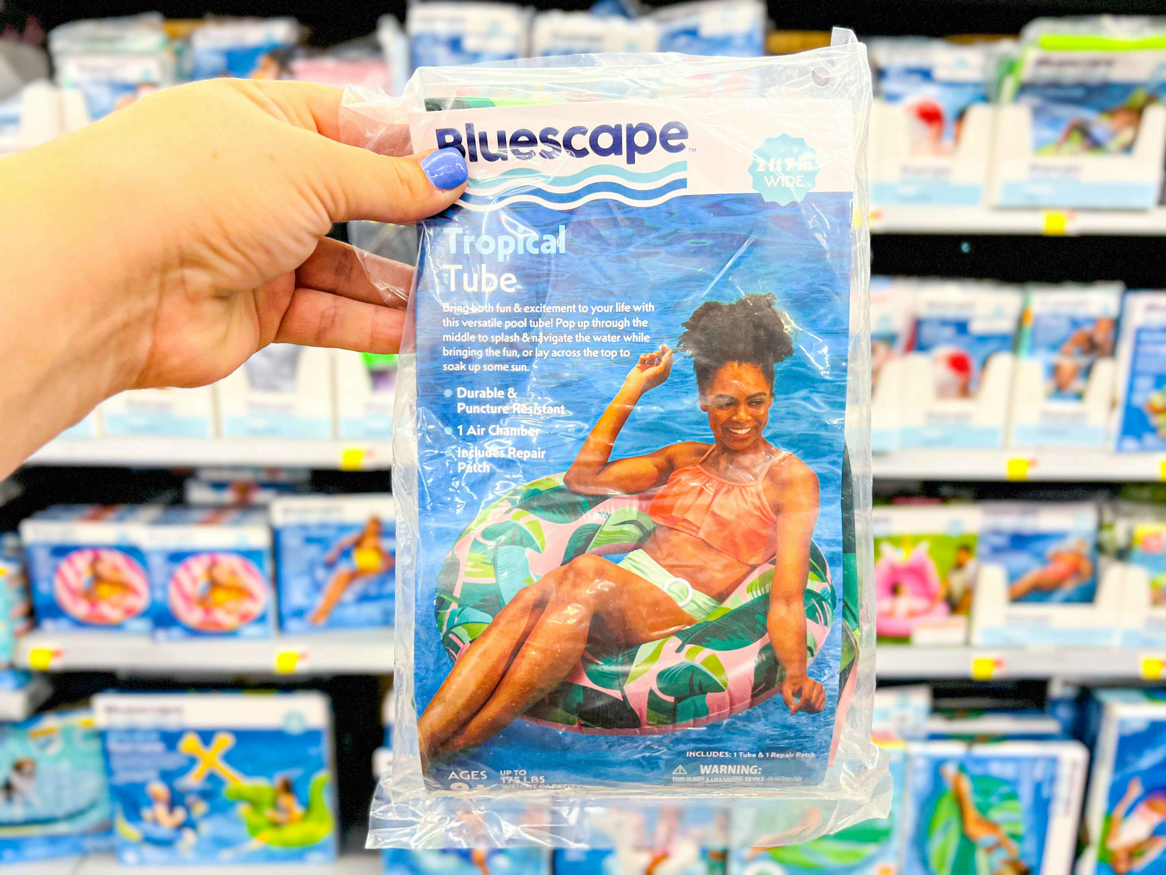 a person's hand holding up a bluescape tropical pool float tube at walmart
