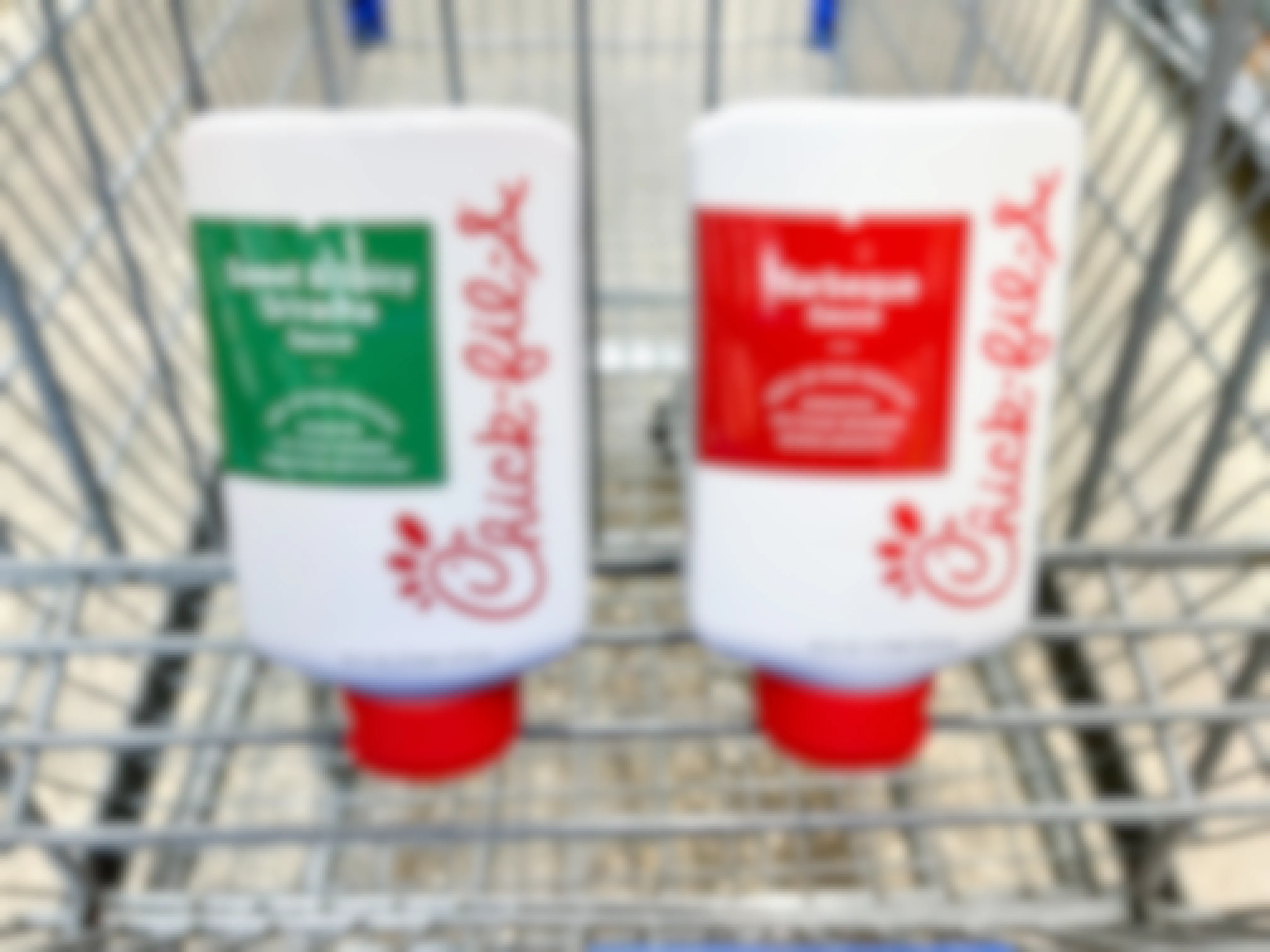 Bottles of Chick-fil-A barbeque and sweet & spicy sriracha sauce in a Walmart cart