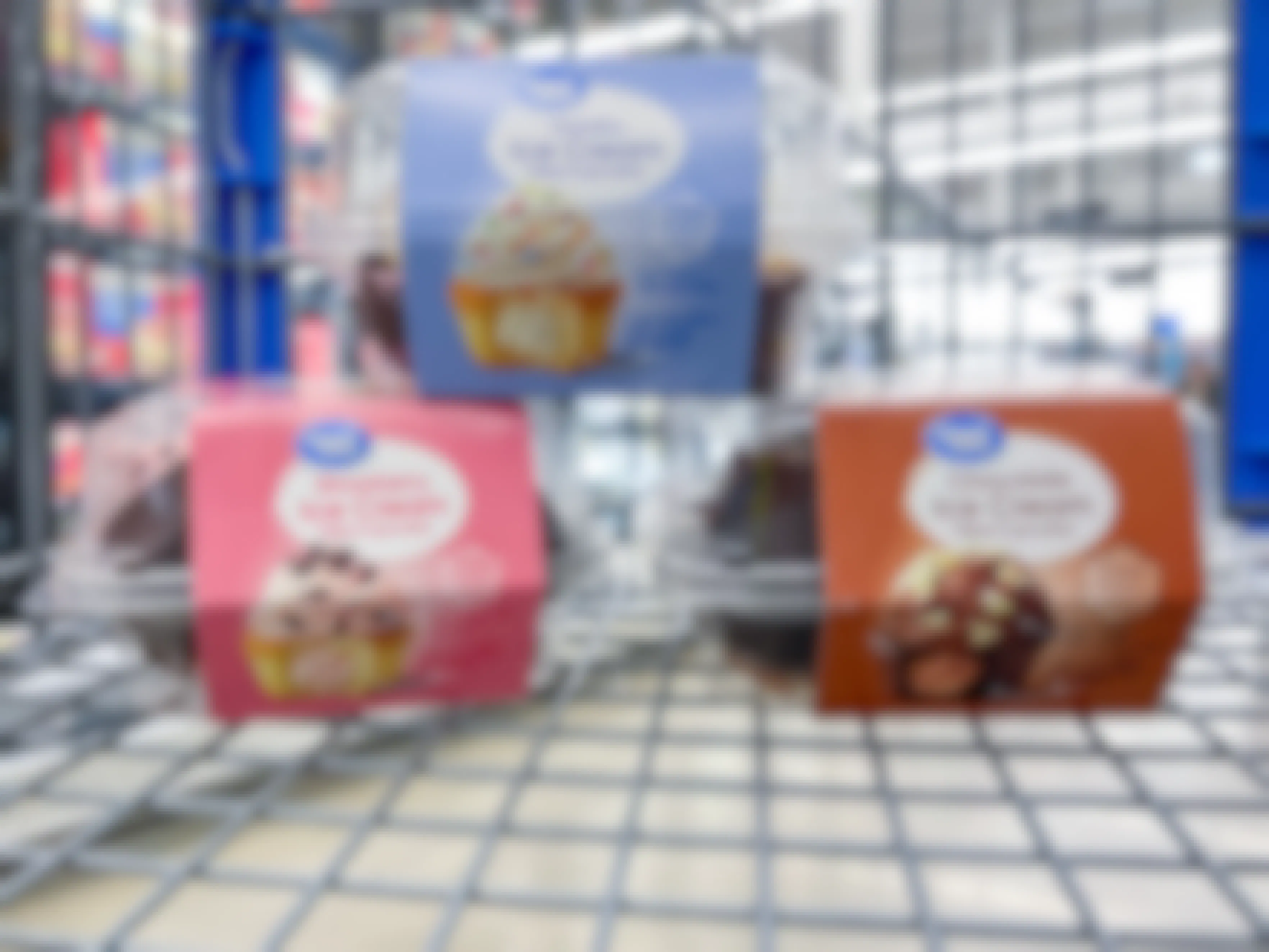Three packs of Great Value Ice Cream Filled Cupcakes in a Walmart shopping cart: Vanilla, Chocolate, and Strawberry flavors