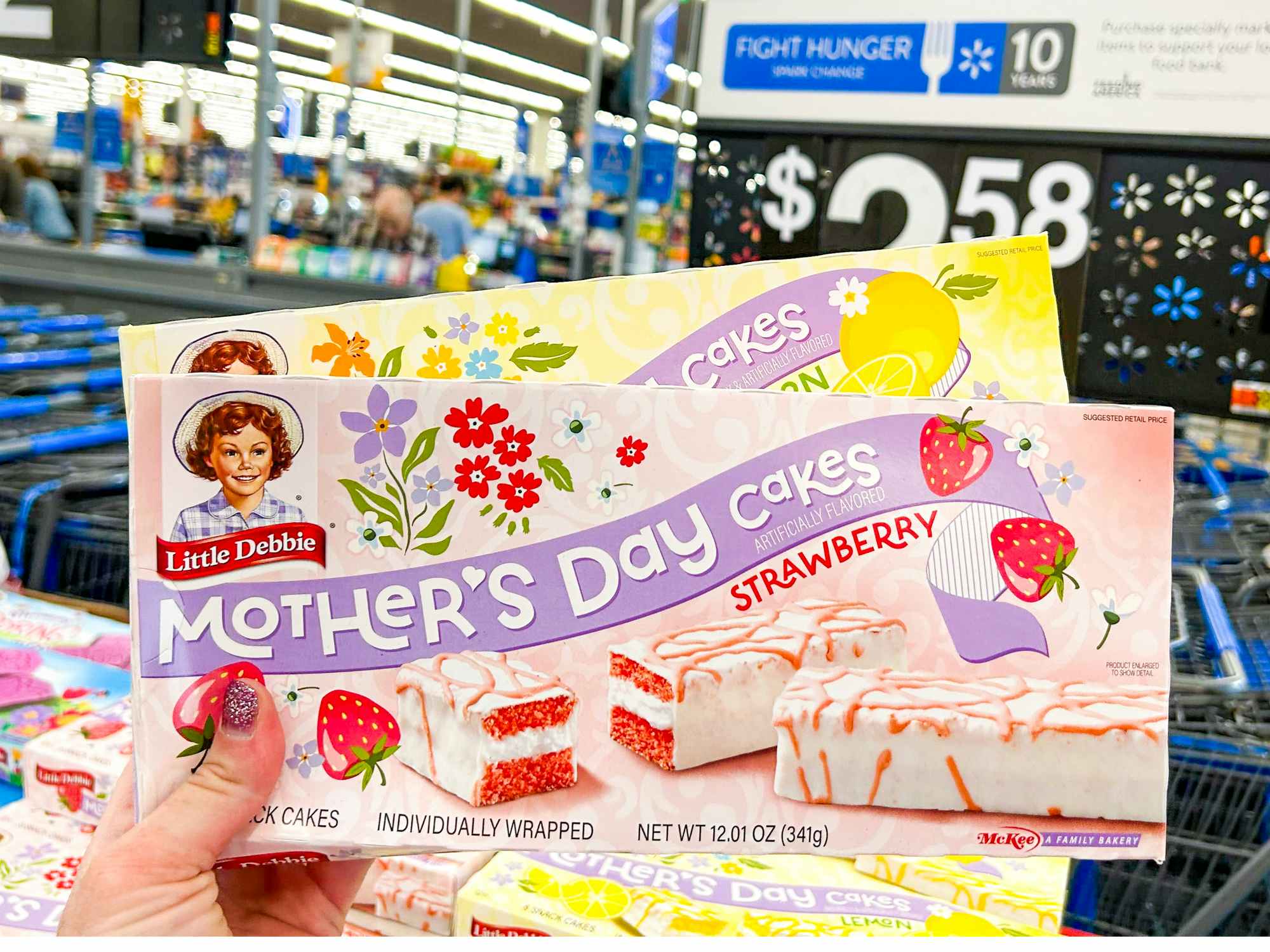 Someone holding boxes of Little Debbie Mother's Day Cakes in Walmart