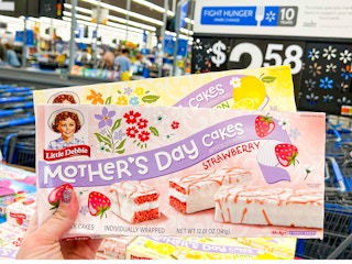 Someone holding boxes of Little Debbie Mother's Day Cakes in Walmart
