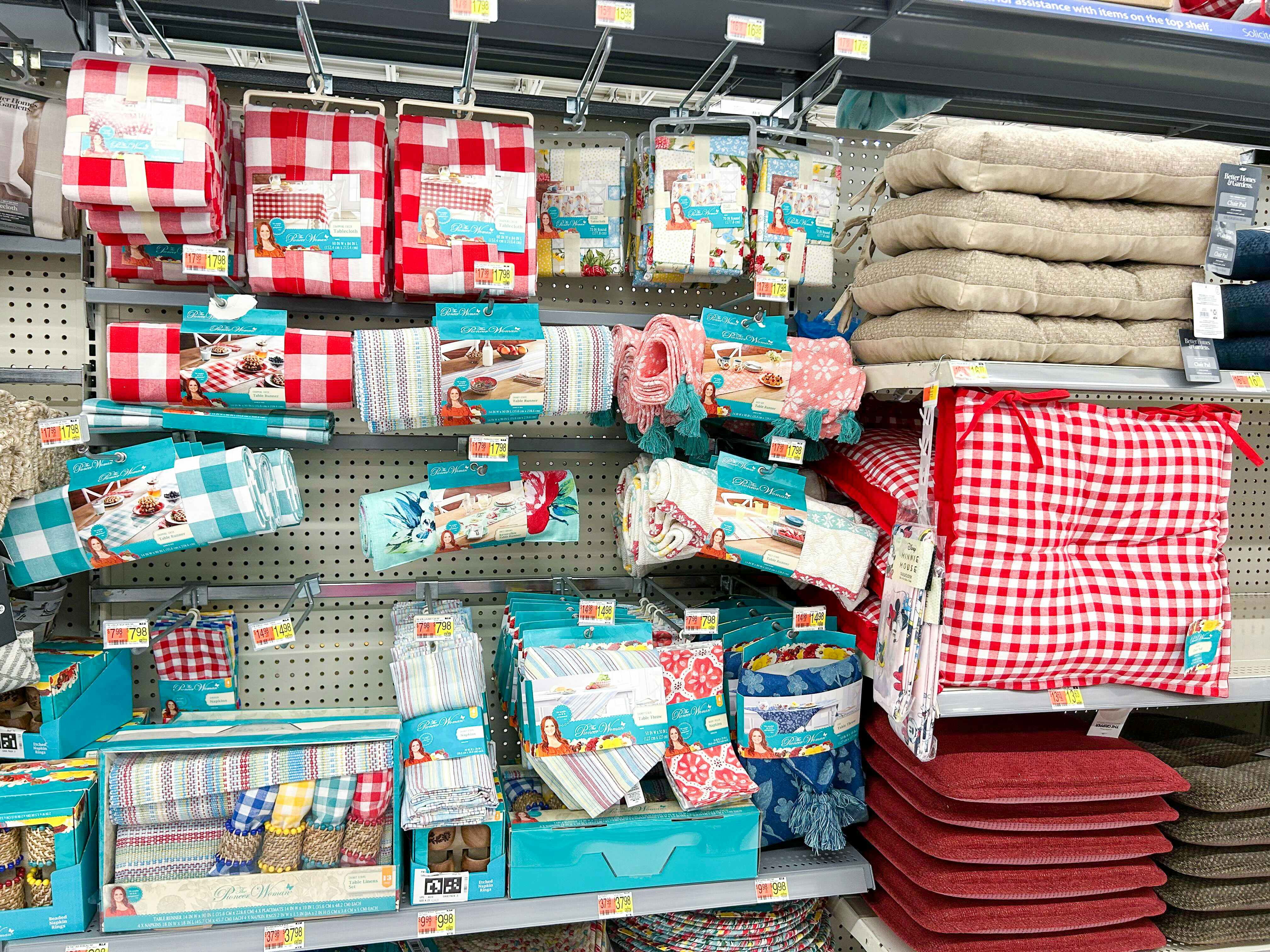 A walmart shelf filled with The Pioneer Woman kitchen and home items, including dish towels, chair cushions, and more